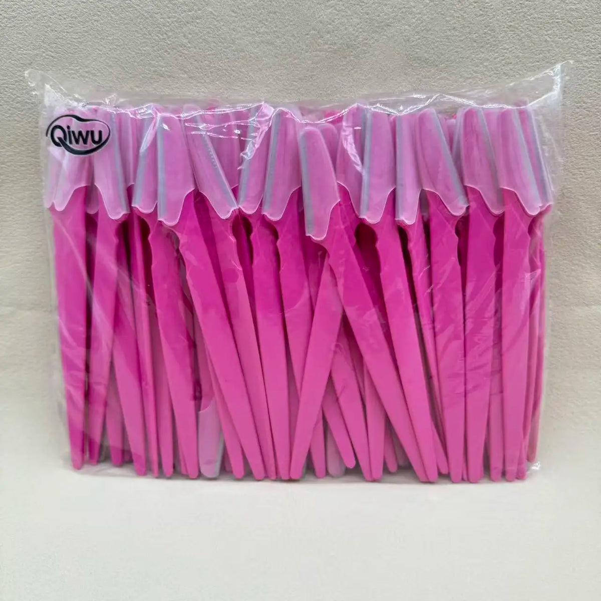 Un emballage en plastique transparent contenant un jeu de ciseaux de précision pour sourcils roses.