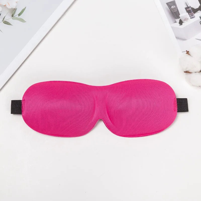A bright pink 3D sleep mask designed for light blocking is displayed on a white surface.
