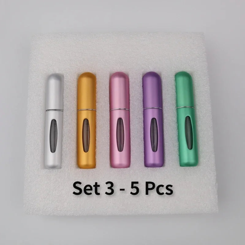 A set of five colorful 5ml travel perfume atomizer bottles arranged on a white, fluffy surface.
