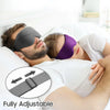 A man and a woman relaxing in bed, one wearing a black sleep mask and the other a purple sleep mask.