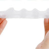 A hand holds a white silicone toe separator designed for foot and bunion relief.