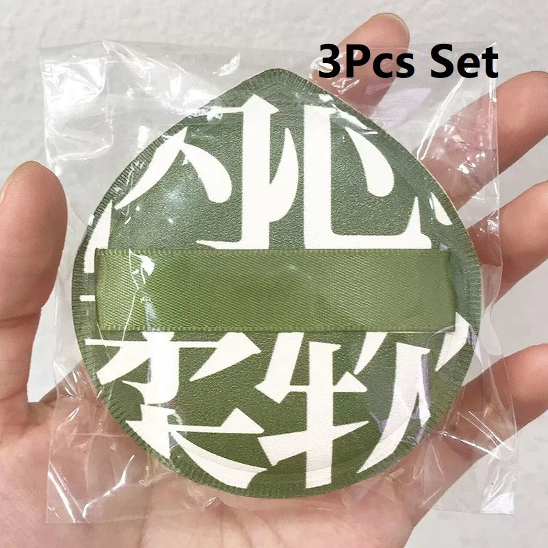 A set of three green and white makeup puffs packaged in a clear plastic bag.