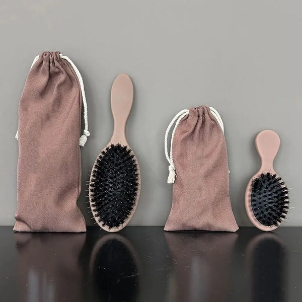 A set of matte boar bristle hair extension brushes in dusty rose color, shown with their fabric bags.
