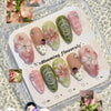 Exhibición de uñas postizas de mariquita verde fresca en 3D con detalles rosa y blanco en una bandeja de acrílico transparent