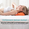 A woman is lying down, using an orange neck and shoulder traction massager for relaxation.