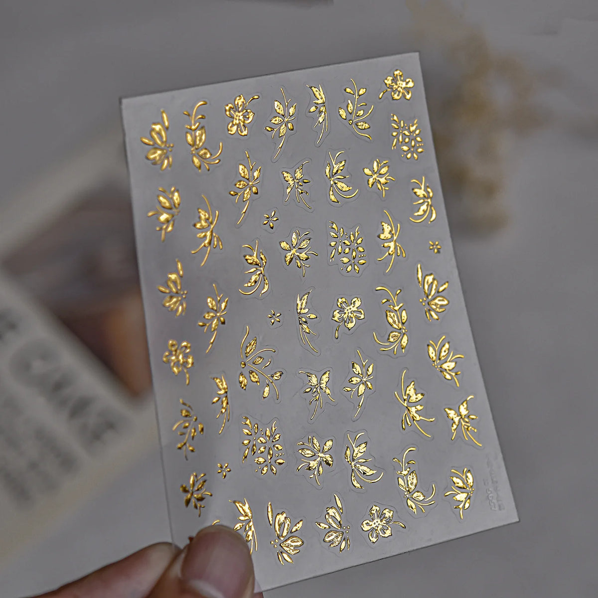 A sheet of luxury metallic gold flower nail art stickers with various floral designs.