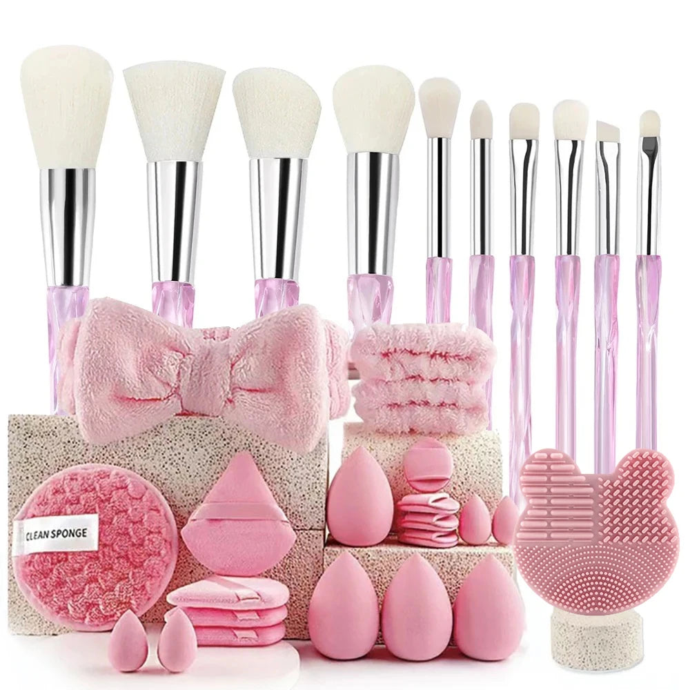 A set of pink beauty sponges, including a large brush and various small applicators, displayed on a textured surface.