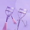 A purple portable eyelash curler tool shown against a light purple background.