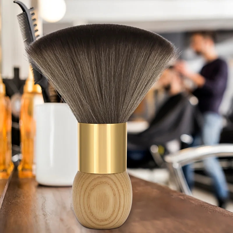 A professional hair duster brush with a wooden handle and gold ferrule resting on a dark surface.