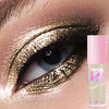 Primer plano de una persona aplicando sombra de ojos metálica dorada brillante con un tubo de producto rosa visible.