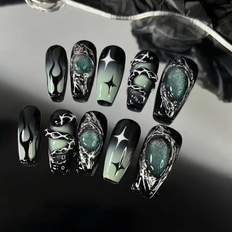 A set of black press-on nails featuring a dark green, marbled finish with silver cross and bow designs.
