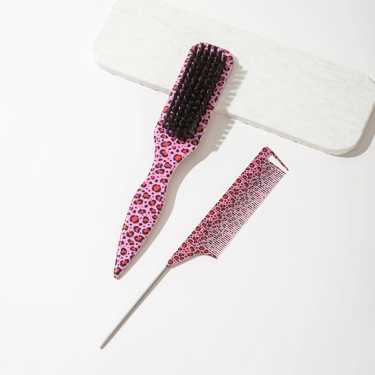 A set of two leopard print pointed tail hair combs, one pink and black, resting on a white surface.