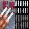 A hand displays a set of 3XL extra long square press-on acrylic false nails in various shades and lengths.