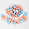 A pile of reusable expandable makeup sponges in various shades of pink and blue.