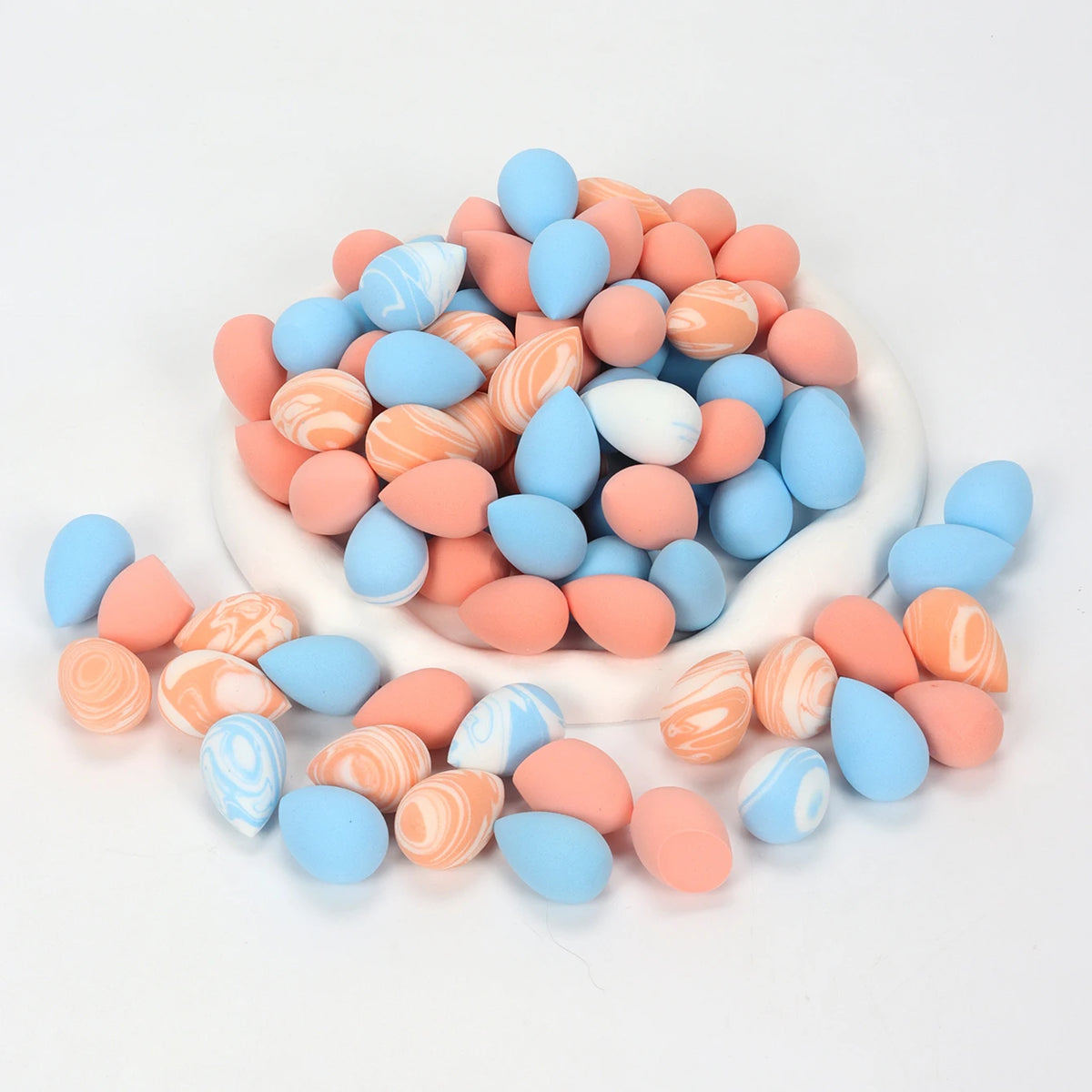 A pile of reusable expandable makeup sponges in various shades of pink and blue.
