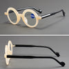 Un par de gafas de lectura con lupa anti-luz azul transparentes, con monturas beige claro y brazos negros.