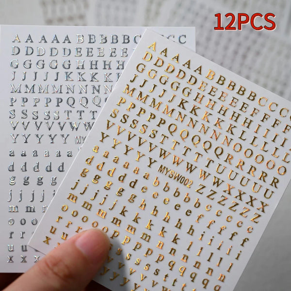 A close-up of 12 pieces of laser gold and silver 3D alphabet nail art stickers showing various letters and symbols.