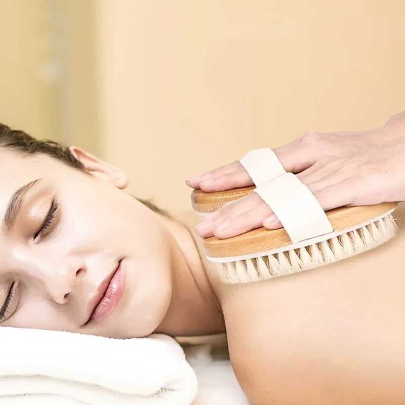 Una mano usa un cepillo exfoliante de cerdas naturales en la piel de una persona.