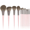A set of professional makeup brushes with soft gray and pink handles and bristles.