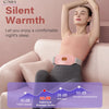A woman is wearing a pink heated abdominal massage device while relaxing on a sofa.