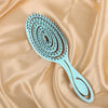 Peigne en silicone bleu clair avec de nombreuses petites dents, sur un fond de tissu pêche fluide.