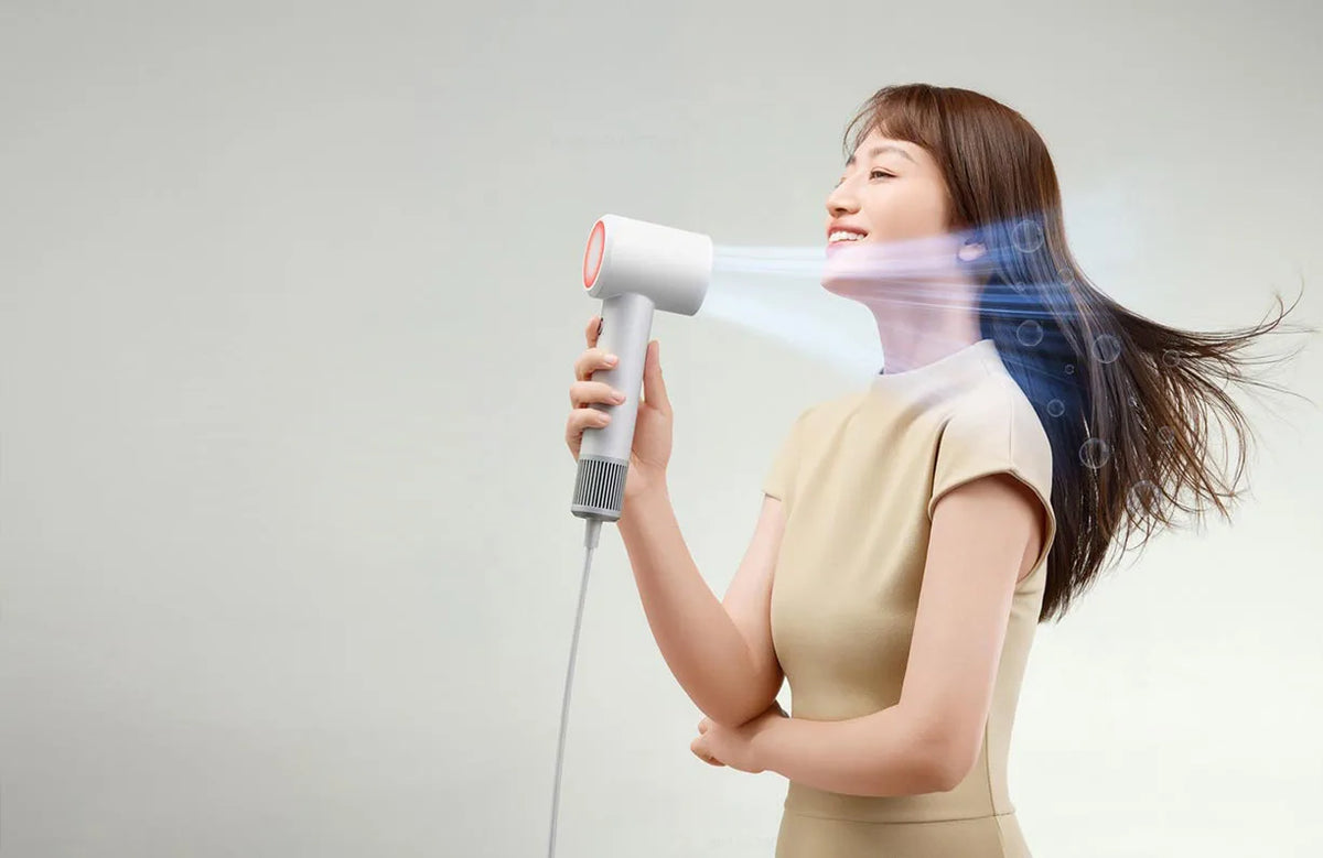 A woman is using a professional high-speed hair dryer to style her hair.