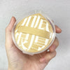 A clear storage box holds a beige makeup puff set with Japanese characters printed on it.