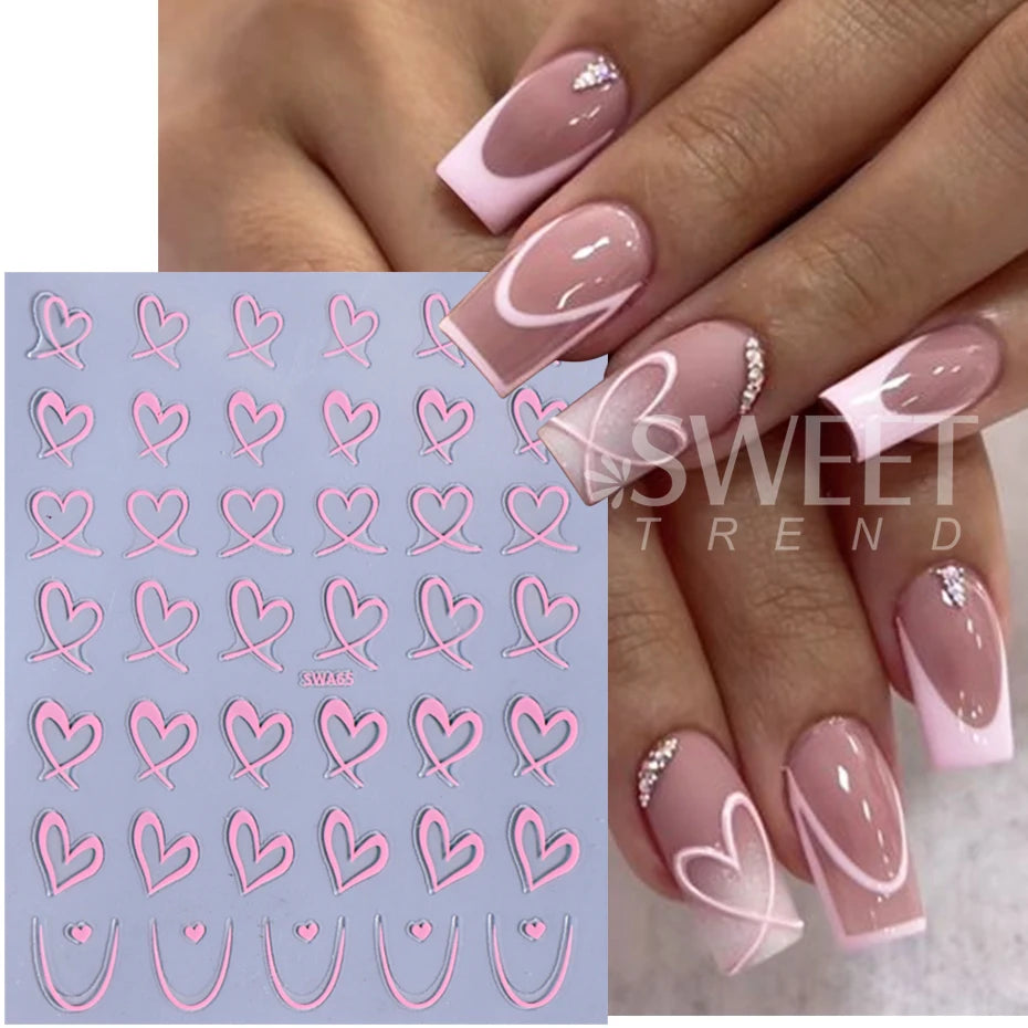 Une main présente une manucure avec des décals de cœurs roses et blancs sur les ongles.