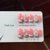 A display of hand-painted pink resin nail art carvings with gold accents in various sizes.