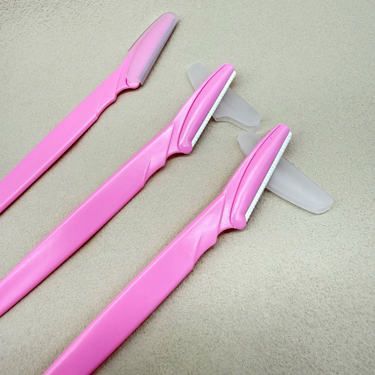 Kit de tondeuse à sourcils rose avec deux outils de coupe en plastique et un guide.