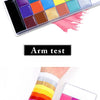 Palette de maquillage professionnel visage et corps avec 20 couleurs, démontrée sur une bande d'essai sur un bras.