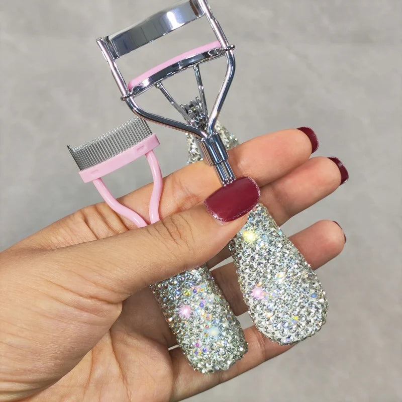 A hand holds a professional eyelash curler set with pink and silver components.