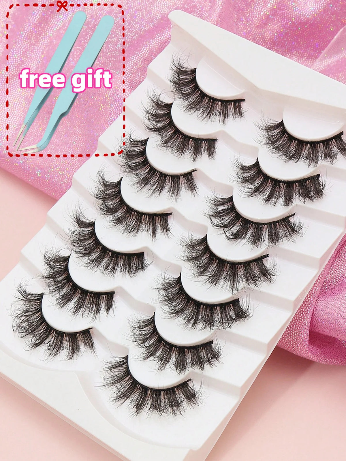 Weißer Wimpern-Tray mit mehreren Paaren schwarzer Mink-Falschwimpern auf rosa Hintergrund.