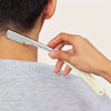 Una mano sostiene una maquinilla de afeitar manual de acero inoxidable con cuchillas de repuesto contra el cuello de una pers