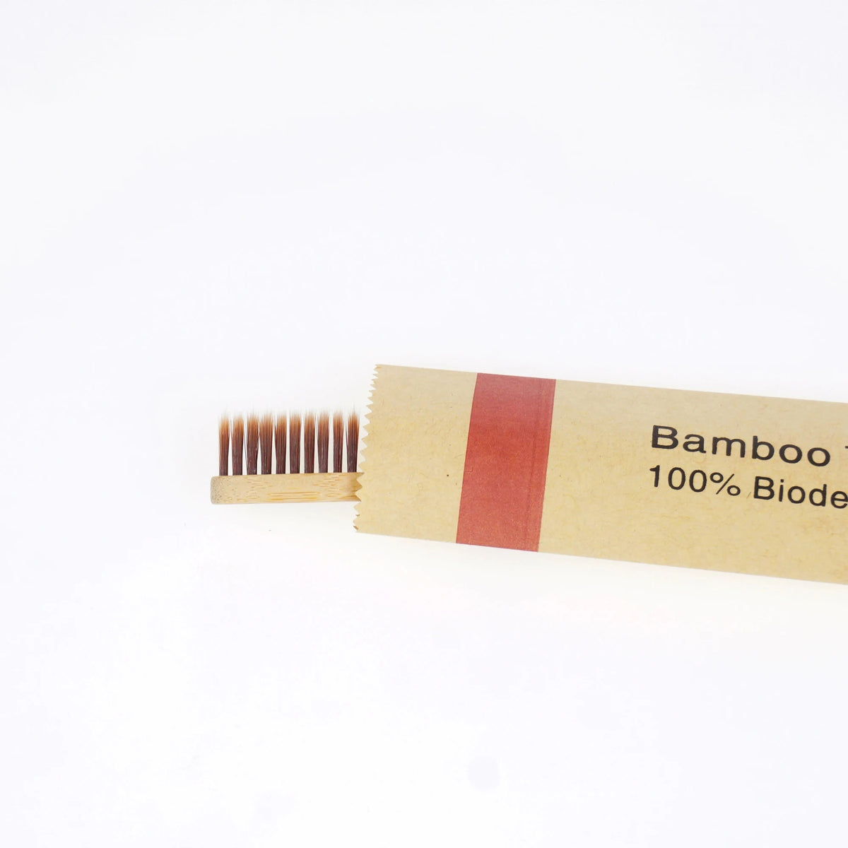 A wooden bamboo toothbrush with soft bristles and a red band is shown on a white background.