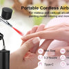 Hands are using a portable cordless airbrush kit to apply paint for nail art or decoration.