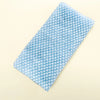 A rectangular blue exfoliating loofah with a white diamond pattern lying on a light background.