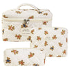 A cream-colored quilted cotton makeup bag with a zipper closure featuring small bear embroidery.
