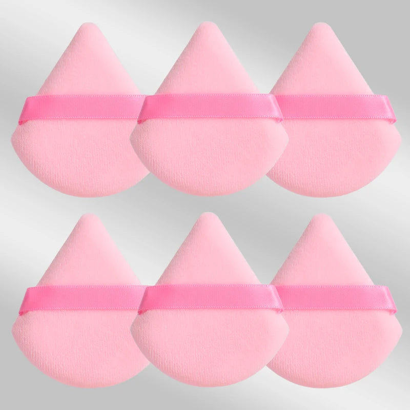 Un set de six éponges de maquillage triangulaires roses avec des élastiques roses.