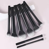 A set of nine black and white makeup brushes displayed on a light background.