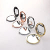 A collection of four portable folding makeup mirrors in silver, rose gold, and gold tones.