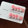 A display of hand-painted pink resin nail art designs in various sizes and shapes with gold accents.