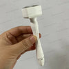A hand holds a white adjustable microneedling derma stamp device with a fine brush head.