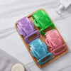 A wooden tray holds five silicone body scrubbers in various colors including purple, green, pink, and blue.