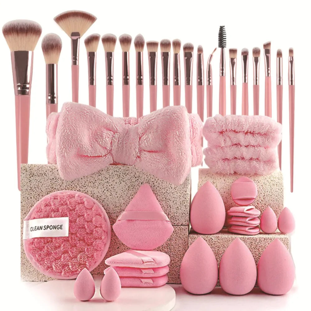 A collection of pink makeup brushes, sponges, and tools arranged on a light background.