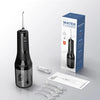 A black portable water flosser device and accessories are shown next to its packaging.
