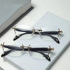 A pair of black retro frameless reading glasses with clear lenses resting on a white surface.