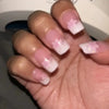 A hand displaying press-on acrylic flower nails with white and pink accents.