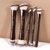 A set of five professional synthetic makeup brushes with dark handles and fluffy brush heads displayed against a neutral back