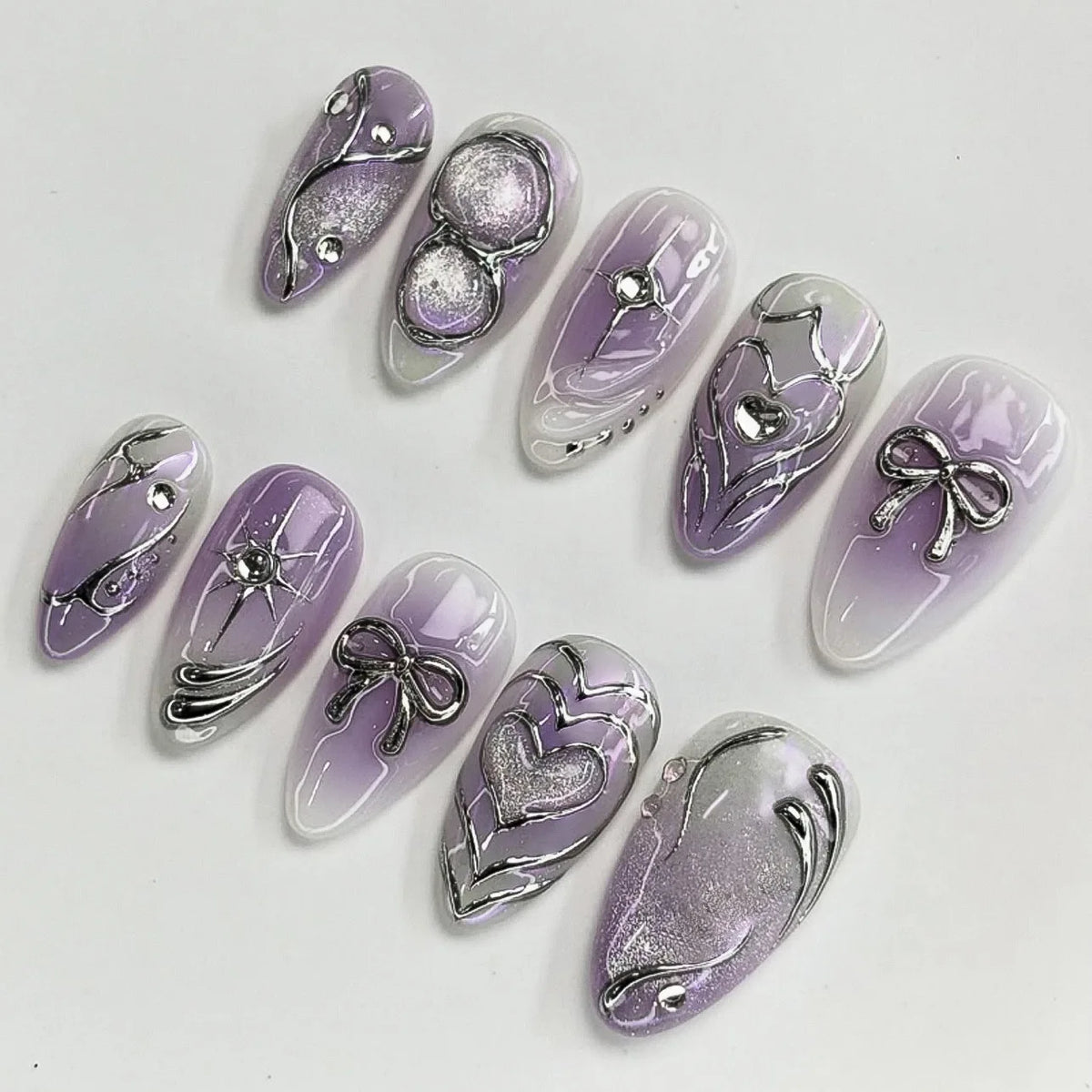 A set of 24 press-on fake nails featuring a lilac gradient and silver heart designs.